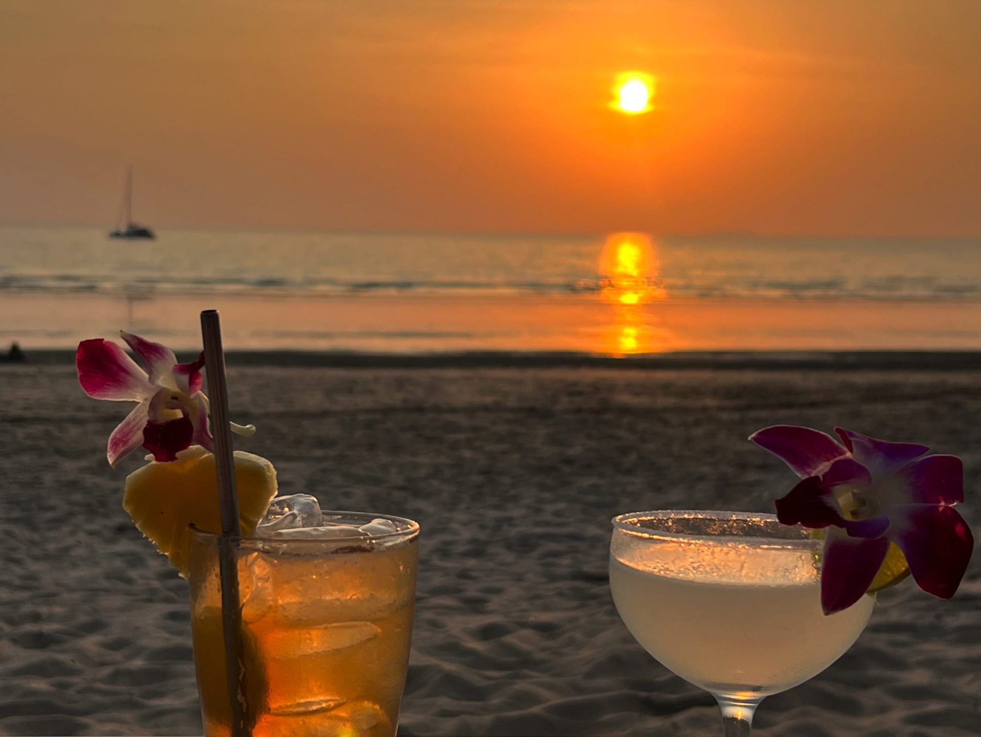 Travel lifestyle photo of cocktails on a beach at sunset in Thailand.
