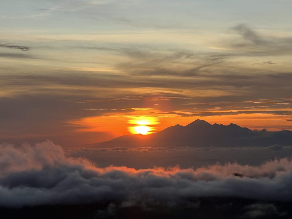 Photo of a golden sunrise taken from the top of Mount Batur, Bali.